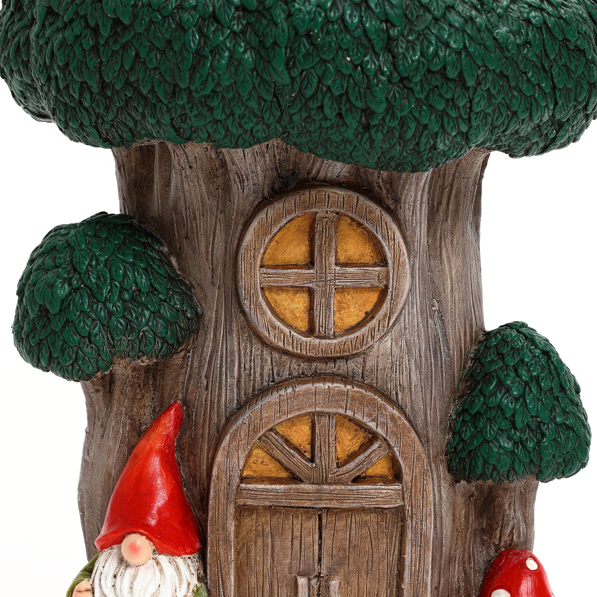 A close-up of a whimsical gnome tree house with a round window, arched door, and two decorative gnomes wearing red hats at the base¡ªperfect inspiration for outdoor space decor.