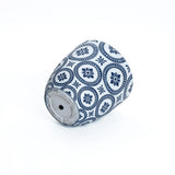 A blue and white pottery piece made of durable MgO material, featuring floral and geometric patterns, rests tilted on its side against a plain background.