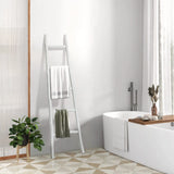 Minimalist bathroom featuring a white freestanding tub, a rustic charm added by a blanket ladder adorned with towels, complemented by a plant and sunlight streaming through the wood-trimmed window.