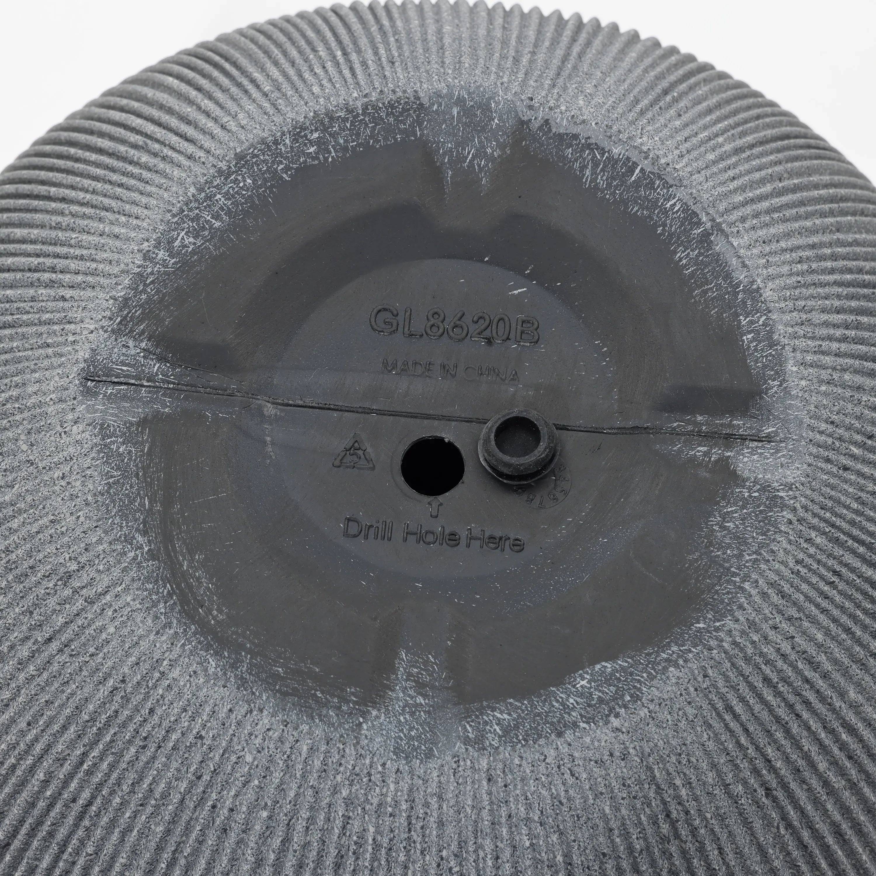 Close-up of a gray textured surface with text GL8620B and Drill Hole Here. A small circular protrusion is near the center, crafted from durable polyethylene, with markings indicating manufacturing origin. Perfect for transforming into a modern planter.