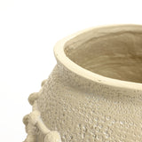 Close-up of a textured, light beige ceramic boho planter with small round protrusions around its upper surface.