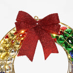 A festive holiday wreath with a large red glittery bow, decorated with gold, red, green, and blue ornaments. Perfect as an outdoor holiday decoration, its enhanced with twinkling LED lights for an extra touch of seasonal magic.