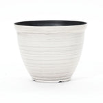 A contemporary planter with a round, ribbed design features a durable plastic construction. This striking piece boasts a black interior and white exterior, set against a plain background.