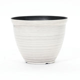 A contemporary planter with a round, ribbed design features a durable plastic construction. This striking piece boasts a black interior and white exterior, set against a plain background.