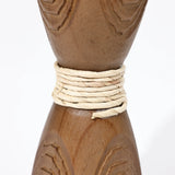Close-up of a handcrafted wooden object with a narrow section wrapped tightly in white cord, showcasing its intricate rattan design.