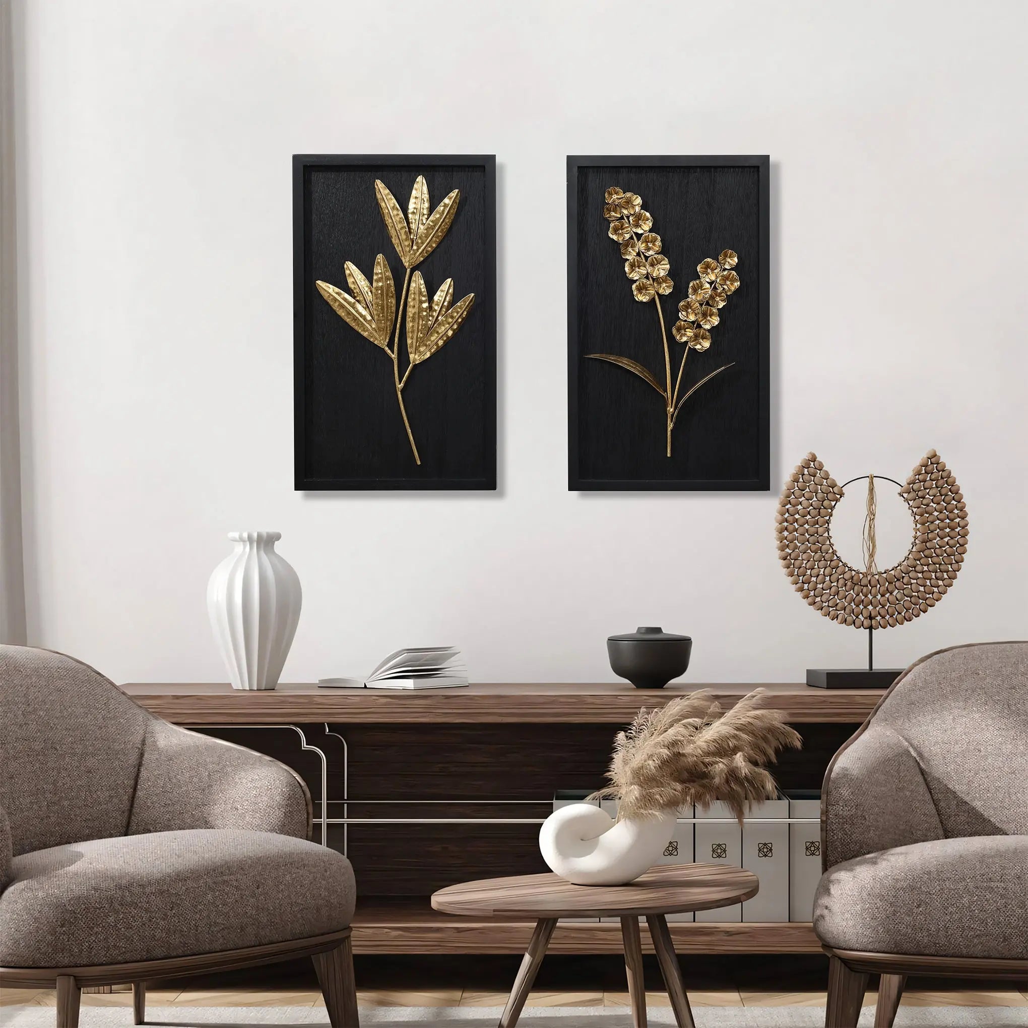 Two decorative panels with gold plant designs hang above a wooden console table, enhancing the wall arts elegance. Two beige chairs and vases filled with flower bouquets are placed nearby, creating a harmonious interior design.