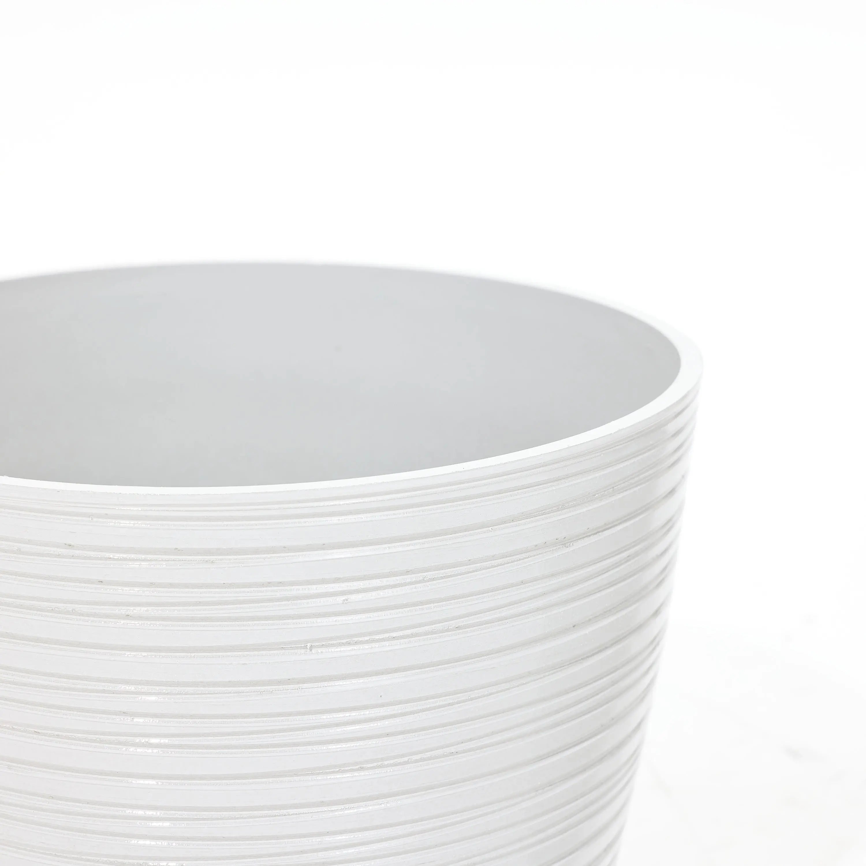 Close-up view of a white ribbed planter, perfect for decorative indoor and outdoor use against a plain background.