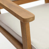 A close-up of a wooden armchairs armrest and part of a white cushioned seat showcases the smooth texture of FSC-certified Acacia wood, epitomizing minimalist design in outdoor furniture.