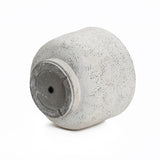 A textured, light gray cylindrical vase lying on its side with a small hole in the base adds a touch of retro minimalist decor.