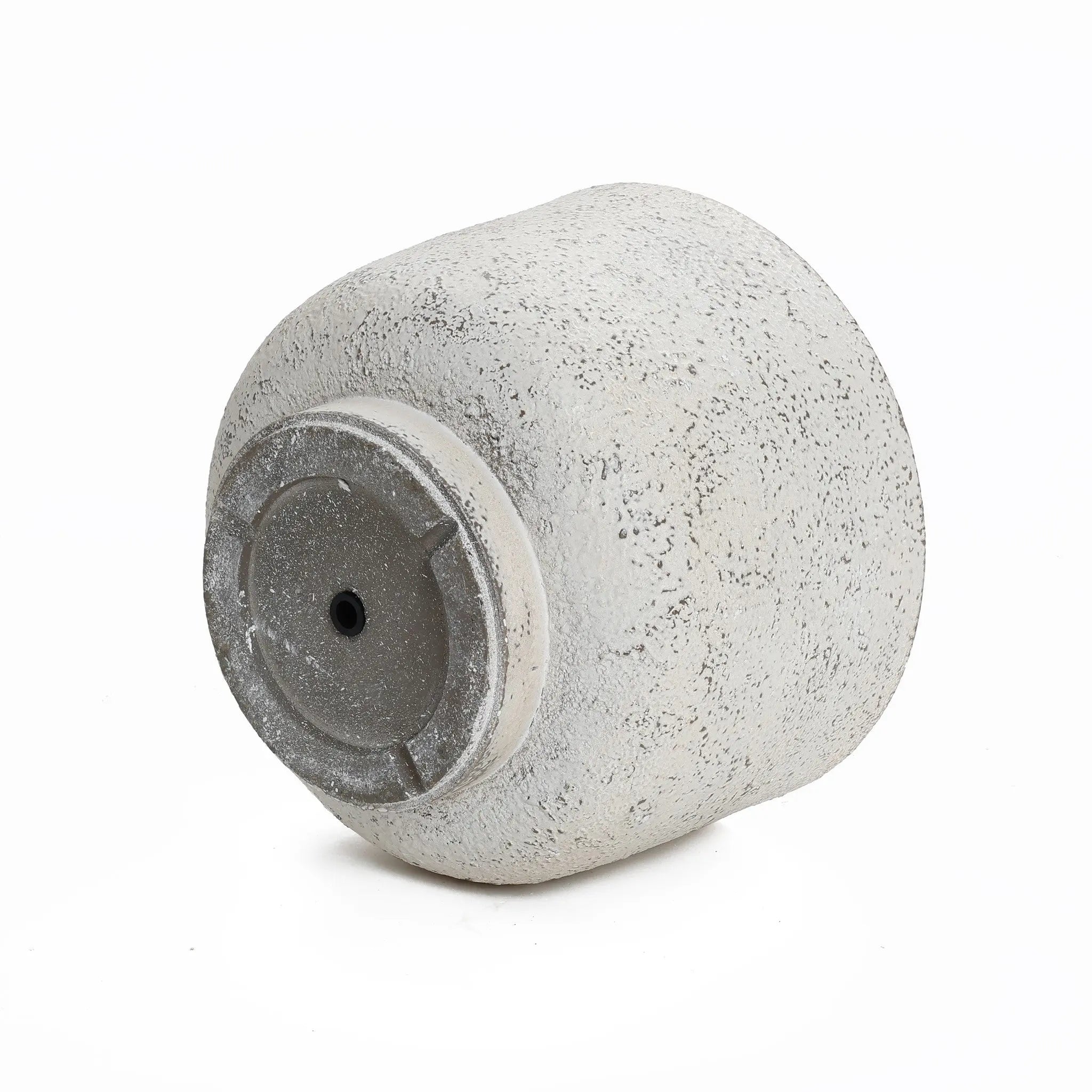A textured, light gray cylindrical vase lying on its side with a small hole in the base adds a touch of retro minimalist decor.