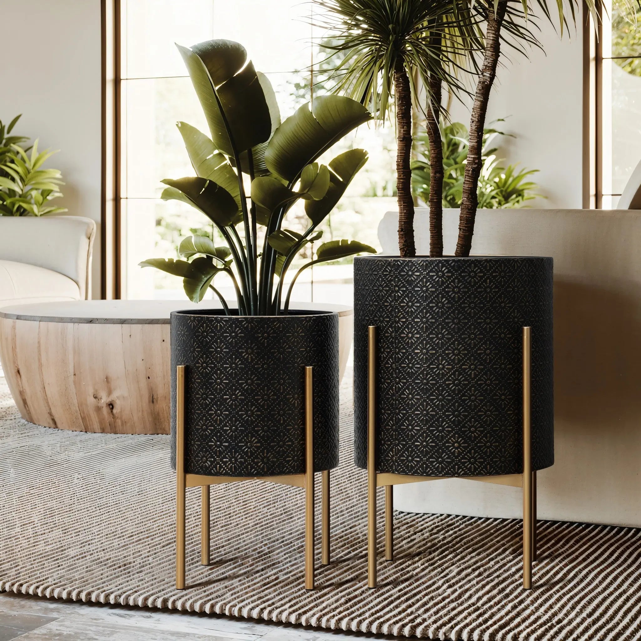 Two elegant planter sets with gold metal stands hold green plants indoors. The room features natural light, a wooden coffee table, and a neutral-toned rug on the floor.