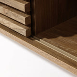 Close-up of a wooden cabinet featuring a sliding door mechanism on a metal track, offering dual-side storage. The edges and grain of the wood are beautifully visible.