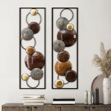 Two vertical handcrafted panels featuring circular metallic and glossy brown elements serve as striking metal wall decor above a console table adorned with vases, books, and dried plants—perfect for contemporary home décor.