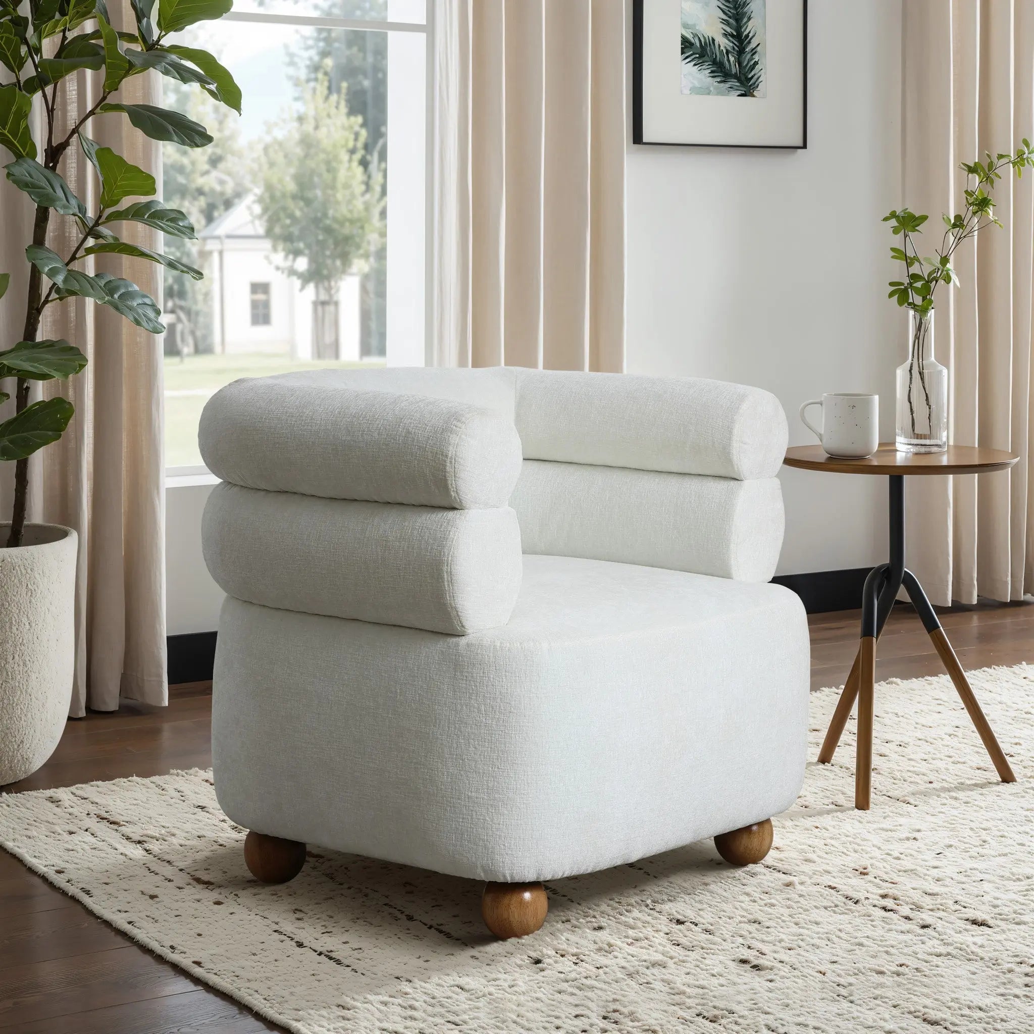 The LuxenHome Tia ivory barrel accent chair with wooden ball legs sits on a textured rug in a sunlit room. Large windows illuminate a side table featuring a mug, potted plants, and framed art on the wall.