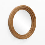 A round rubberwood framed mirror with a thick wooden border is elegantly mounted on a white wall, creating an optical illusion of expanded space.