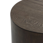 Close-up of a round wooden table with a dark finish, showcasing visible wood grain patterns, exuding rustic charm.