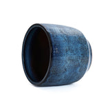 The LuxenHome Ocean blue glazed round ceramic planter, 13.98 h, features a textured grid pattern on its artistic dark blue exterior and a contrasting dark interior, enhancing its modern design.