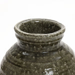 Close-up of a textured, dark green stoneware vase with a wide, slightly flared opening, exuding rustic charm. Perfect for floral arrangements, its set against a plain white background.