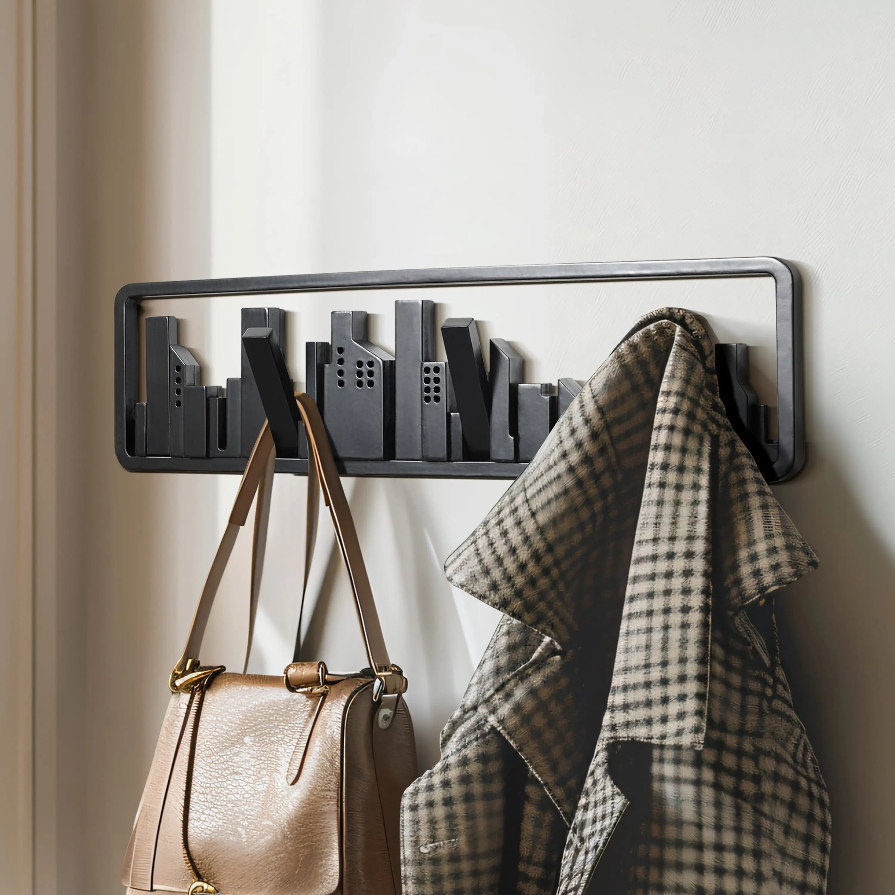 Wall-mounted coat rack crafted from solid fir wood, shaped like a city skyline, with clever flip-down hooks holding a plaid coat and a tan handbag.