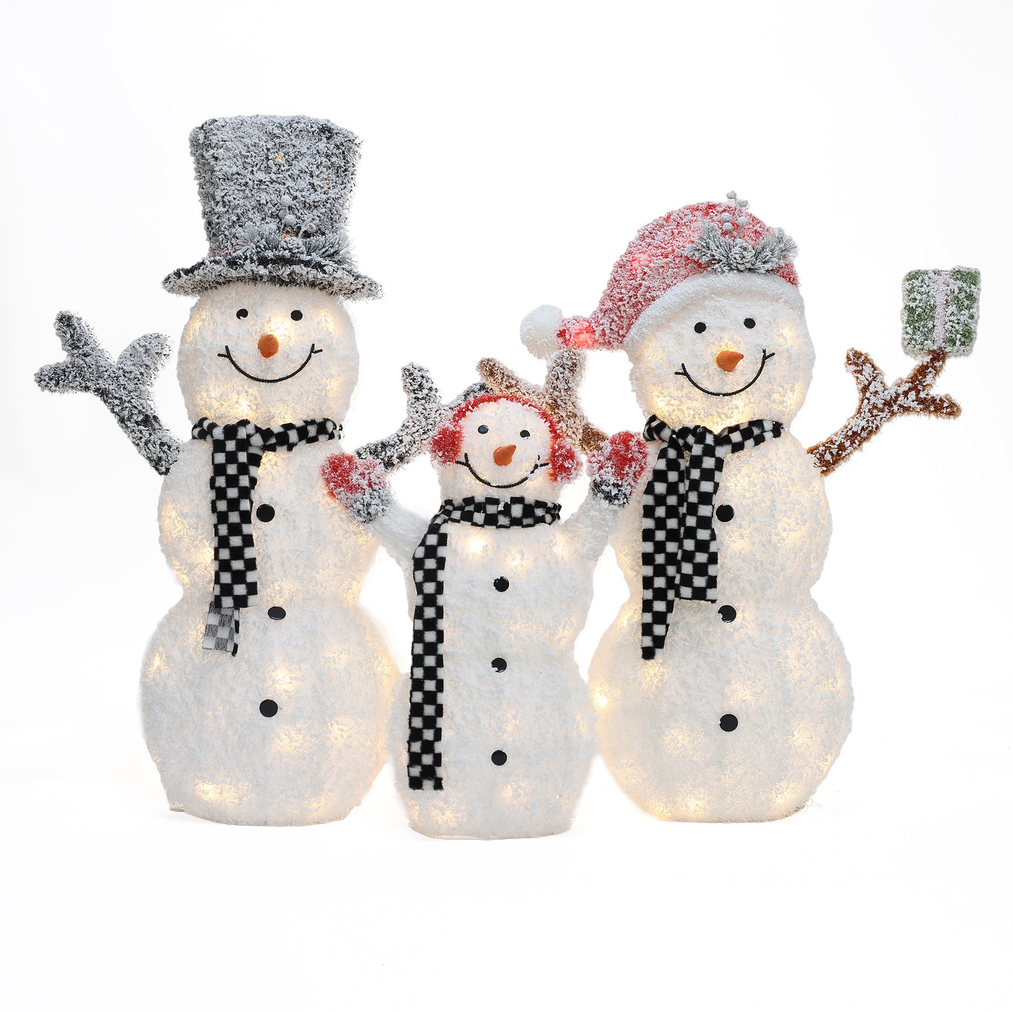 Three illuminated snowmen with checkered scarves make a charming outdoor Christmas decor set; one wears a top hat, one a Santa hat, and the smallest has earmuffs. The snowman on the right holds a small green present.