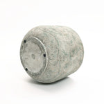 The LuxenHome Rustic Multi-Color Cement 14-Inch Round Planter is a large, cylindrical stone sculpture with textured wavy lines and a smooth base featuring four small black dots around a central circle, set against a plain white background.
