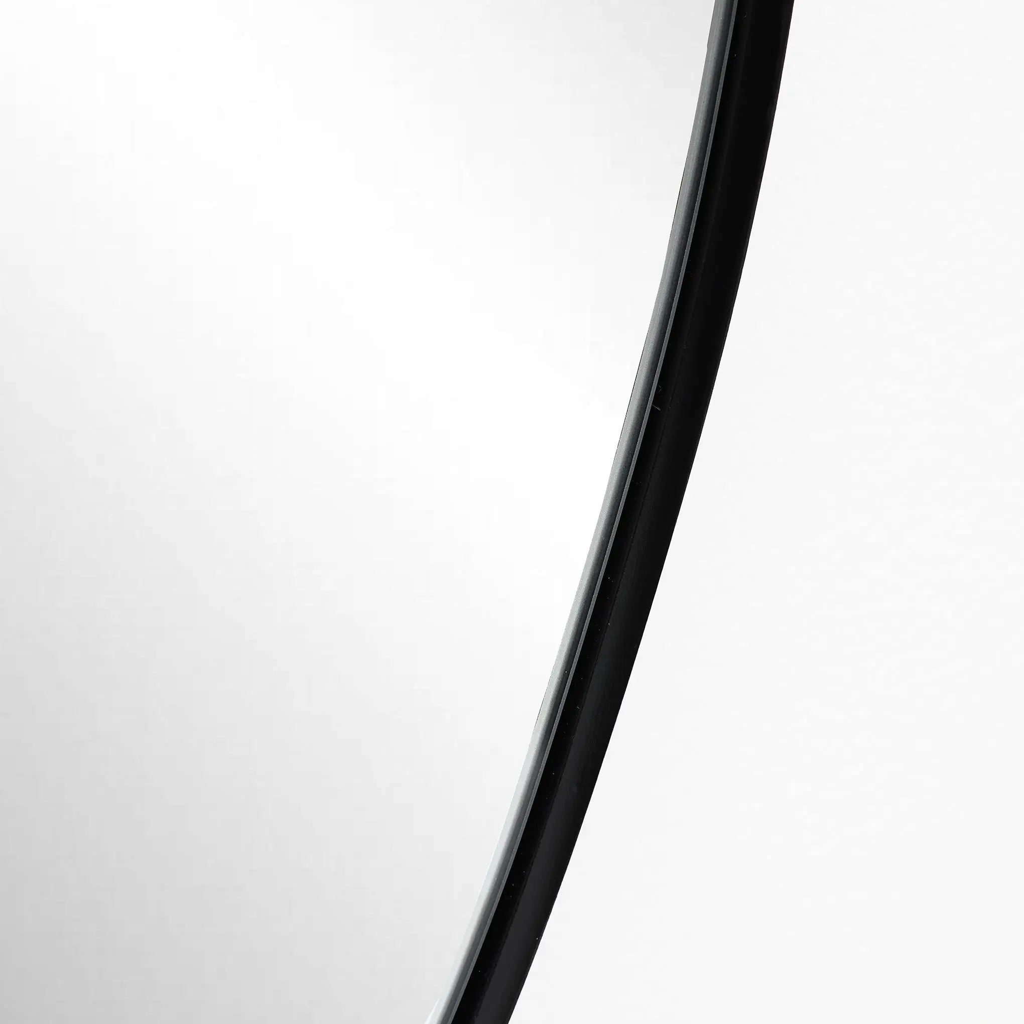 Close-up of a black curved line against a white background, exuding a modern aesthetic reminiscent of the sleek edge of an irregular oval mirror.