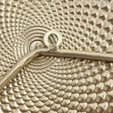 Close-up of a textured metallic pattern resembling a spiral, with a central metal rod and loop integrated into the design, evoking the charm of vintage metal wall decoration.