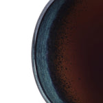 A close-up of a dark liquid in the LuxenHomes Marina gray glazed round ceramic planter, 11.22 h, showcases subtle reflections on its smooth blue and black gradient inner rim.
