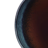 A close-up of a dark liquid in the LuxenHomes Marina gray glazed round ceramic planter, 11.22 h, showcases subtle reflections on its smooth blue and black gradient inner rim.