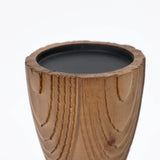 Handcrafted wooden candle holder featuring a carved texture with a hint of rattan design, elegantly holding a black candle.