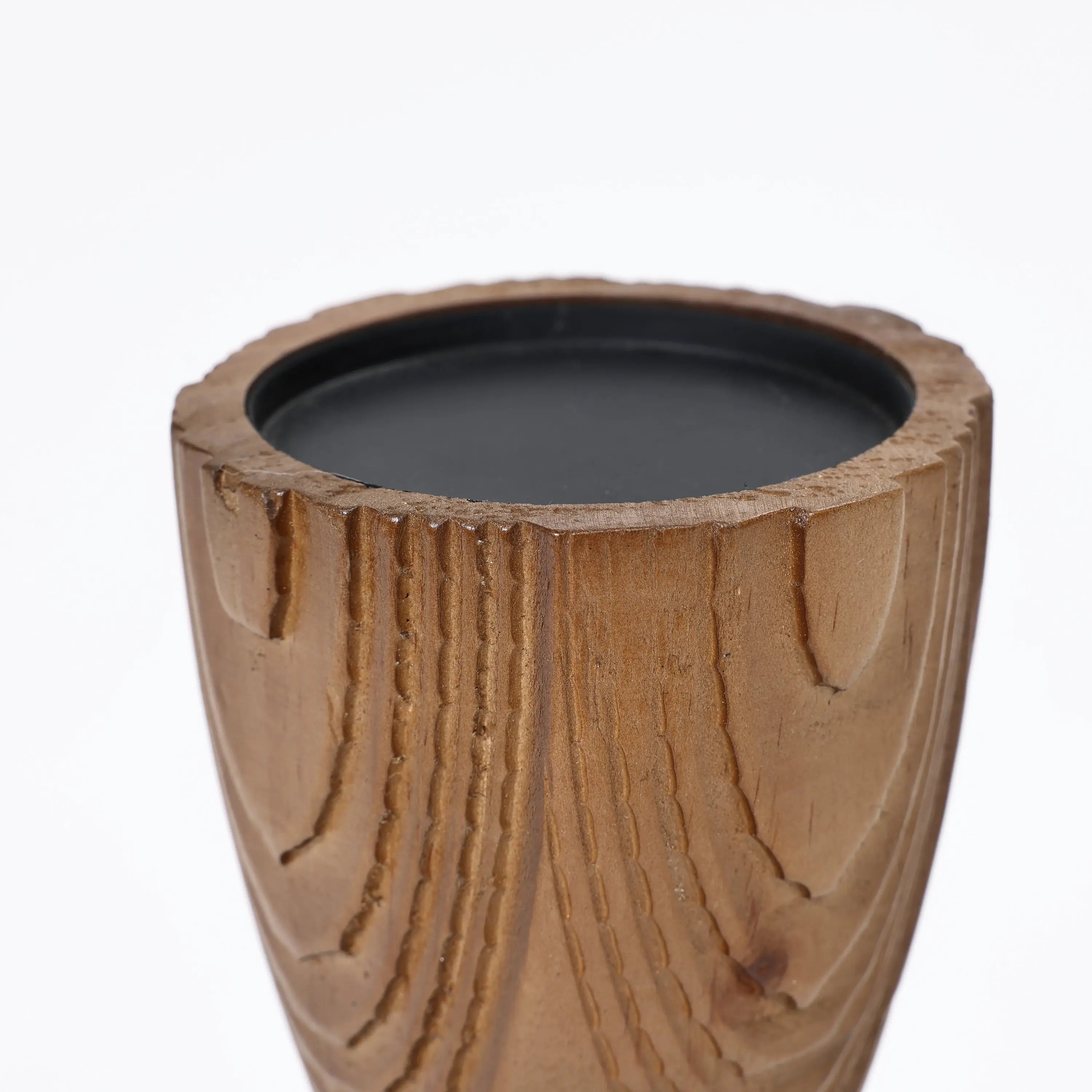 Handcrafted wooden candle holder featuring a carved texture with a hint of rattan design, elegantly holding a black candle.