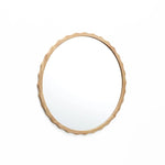 A round mirror with a scalloped design and wooden frame featuring a wavy edge, gracefully hung on a white wall.