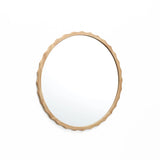 A round mirror with a scalloped design and wooden frame featuring a wavy edge, gracefully hung on a white wall.