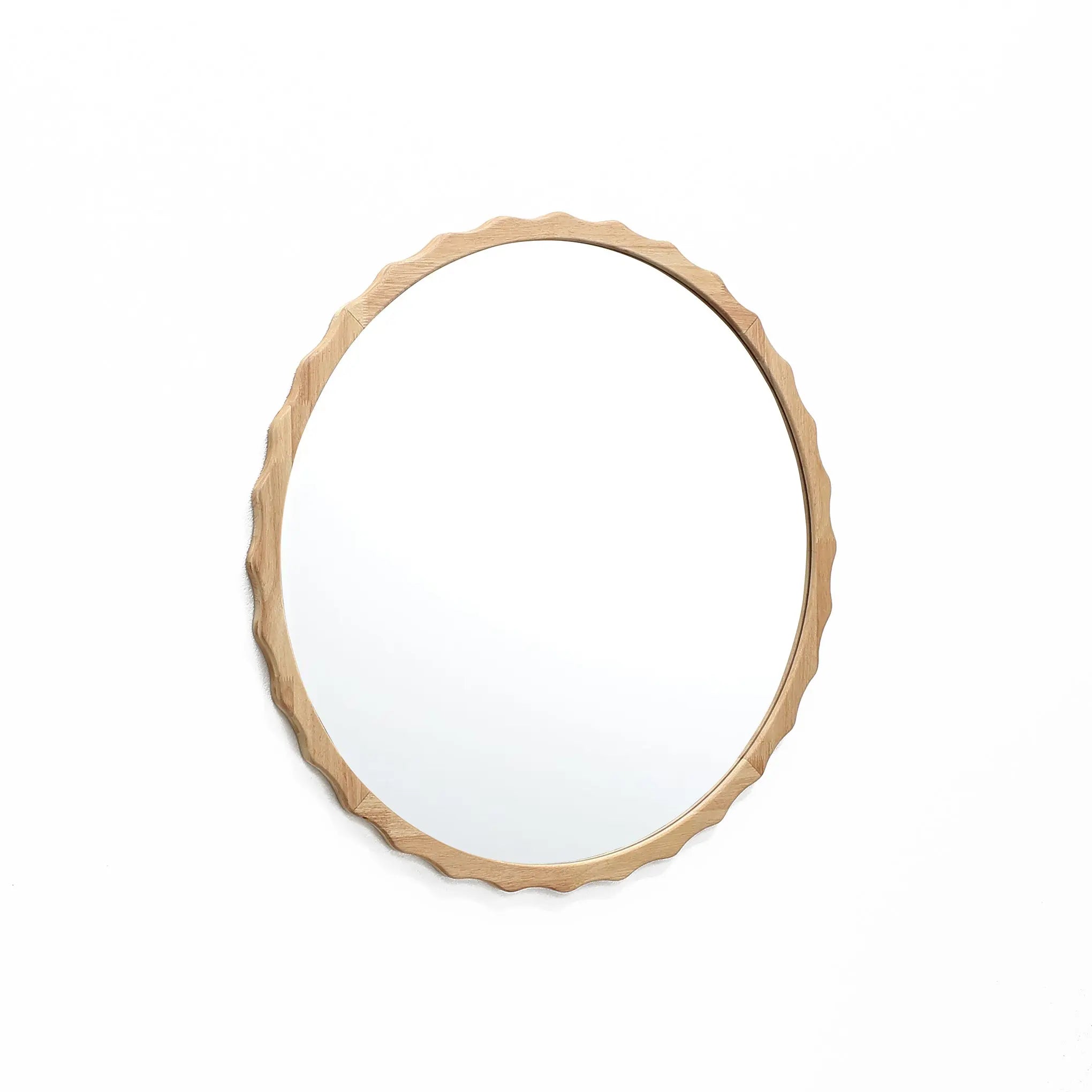 A round mirror with a scalloped design and wooden frame featuring a wavy edge, gracefully hung on a white wall.