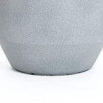 Close-up image of the bottom of a textured, light gray, rounded planter crafted from high-quality MGO material, placed on a white surface.