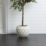 A tree with a slender trunk in a LuxenHome 11.81 high round planter with white and beige geometric patterns stands on a dark gray floor against a white paneled wall, creating a minimalist and elegant indoor setting.