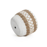 A round, white planter crafted from magnesium oxide, featuring textured patterns and decorative brown rope wrapping, lies on its side.