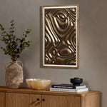 A decorative wooden cabinet with a ceramic vase and bowl is topped with books and a candle. Above, a gold metal abstract wall decor hangs, adding elegance to the modern home decor.