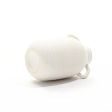 A vintage ceramic vase lies on its side against a plain white background, exuding rustic charm with its timeless design.