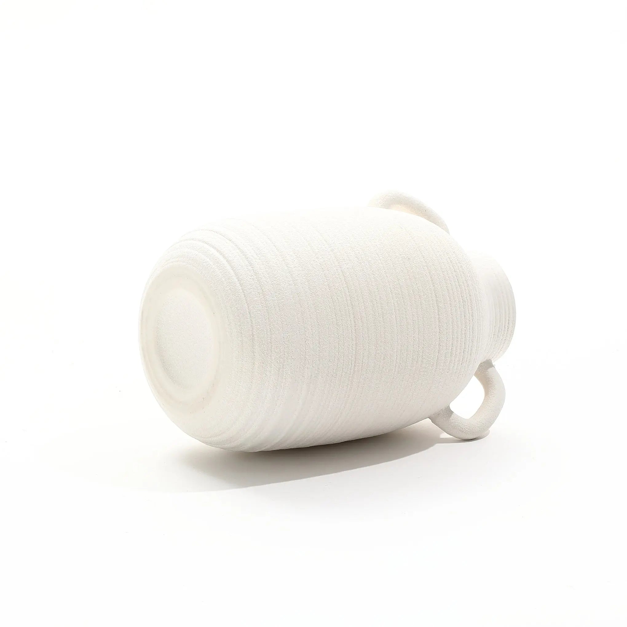 A vintage ceramic vase lies on its side against a plain white background, exuding rustic charm with its timeless design.