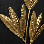 Gold metal leaves on a dark background, featuring a textured and hammered design, make for stunning wall art that can elevate any interior design.