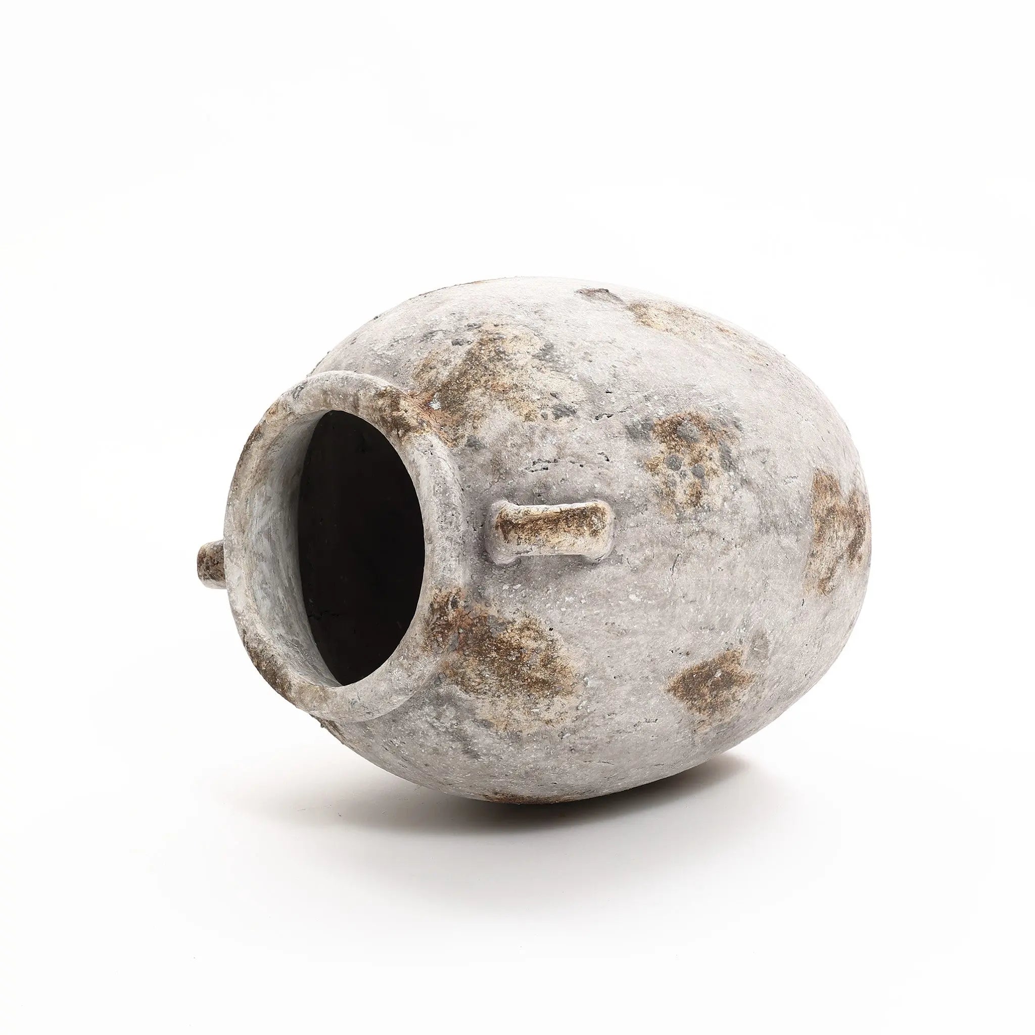 A weathered, oval-shaped terracotta ceramic pot with a wide opening and two small handles lying on its side, exuding vintage appeal.
