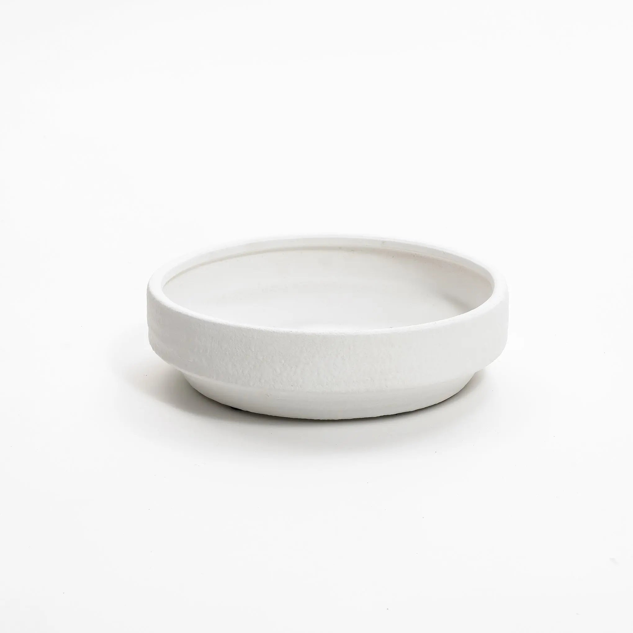 A plain, round ceramic vase seamlessly melds with a white background.