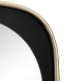 Close-up of an elongated mirror with a rounded, light gold frame against a black background, offering distortion-free viewing and a contemporary touch.