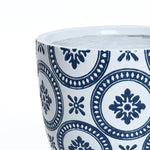 A round ceramic pot with a white base features a pattern of dark blue circular and floral motifs, designed as a tapered planter with a drainage hole for optimal plant health.