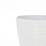 Close-up of the textured upper edge of a white ceramic decorative planter, perfect for indoor and outdoor use, against a plain background.