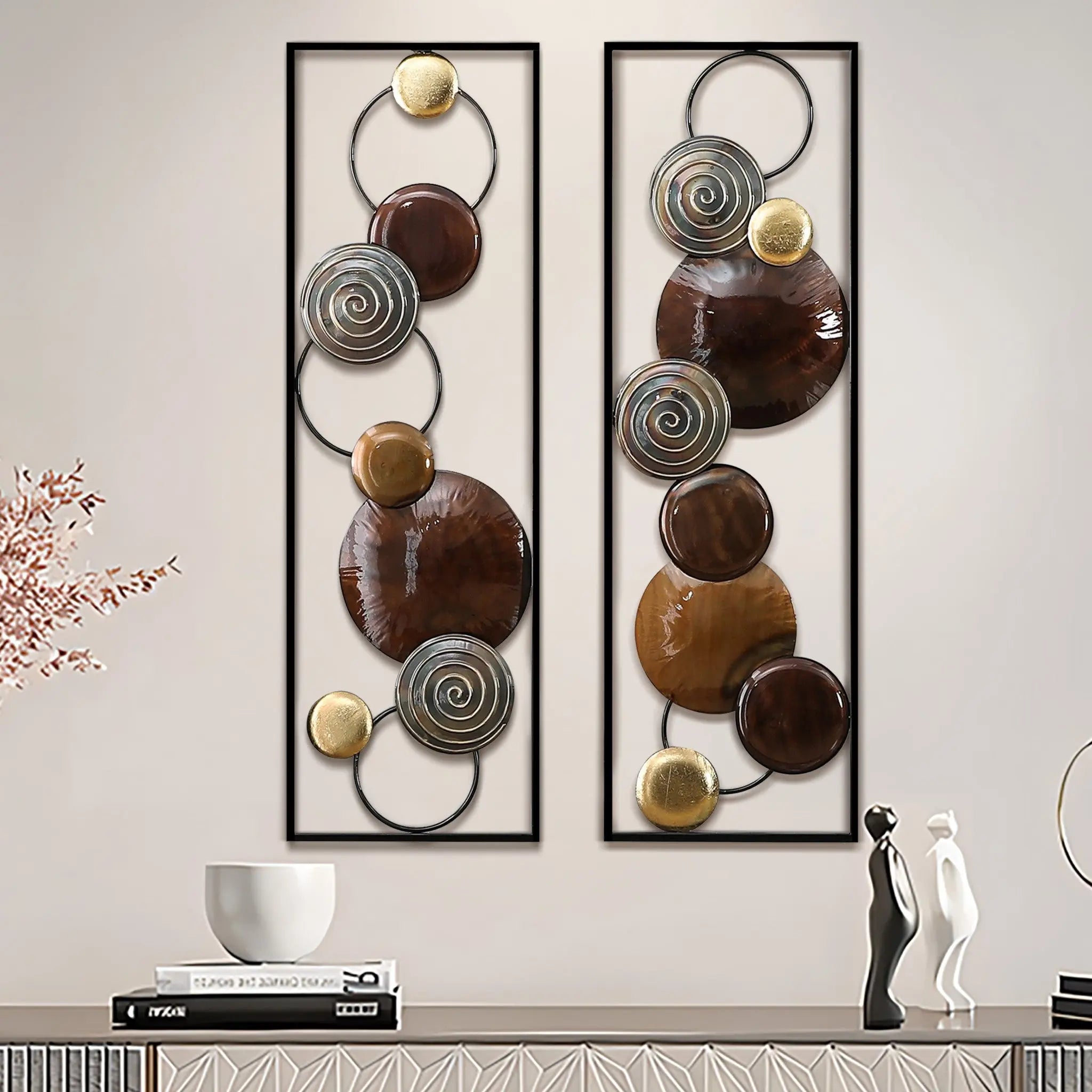 Two rectangular metal wall art pieces with circular and spiral elements in brown, gold, and silver tones create striking metal wall decor above a modern console table with decorative items.
