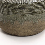 The LuxenHome Rustic Brown Stoneware Bowl Vase features a rough, earthy terracotta base with a textured charm. A glazed upper section in green and gray adds a natural touch with its dripping effect, making this vase an exquisite piece of home decor.