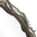 Close-up of a circular metallic frame with a wavy, textured surface and small bead-like details along the edges, echoing the modern romantic style.