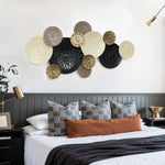 Bedroom with a modern design, featuring geometric throw pillows and a rust-colored cushion. Coastal abstract wall art hangs above the bed, complementing the gold lamps and lush plant on the bedside tables.